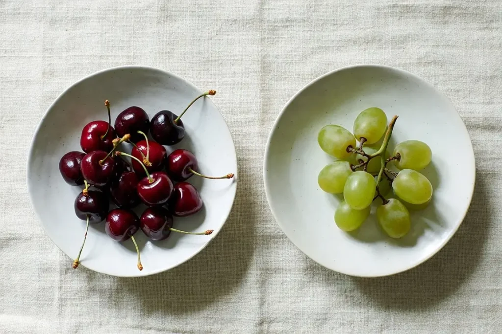 Cherries and grapes side by side, photographed for nutritional comparison