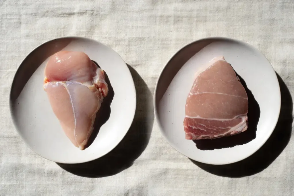Chicken breast and pork tenderloin side by side, photographed for nutritional comparison