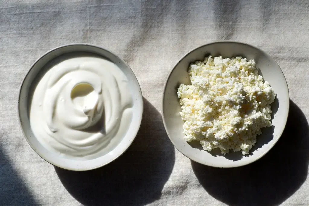 Greek yogurt and cottage cheese side by side, photographed for nutritional comparison