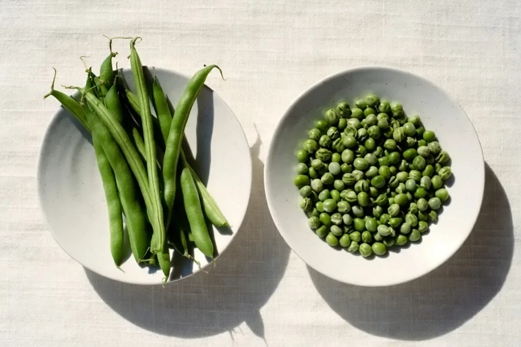 Green beans and green peas side by side, photographed for nutritional comparison