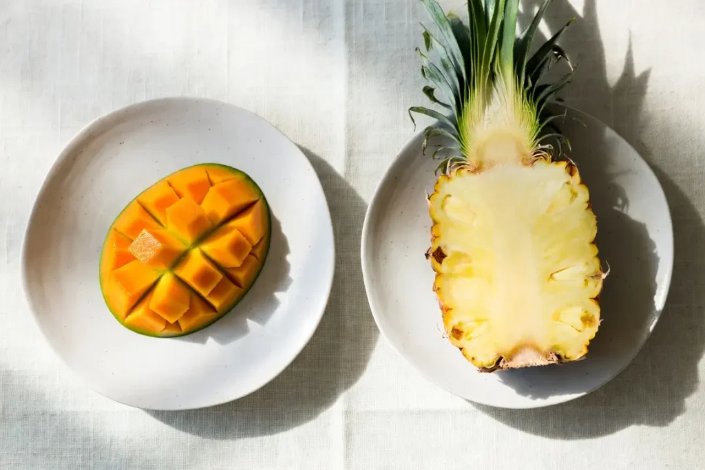 Mango and pineapple side by side, photographed for nutritional comparison