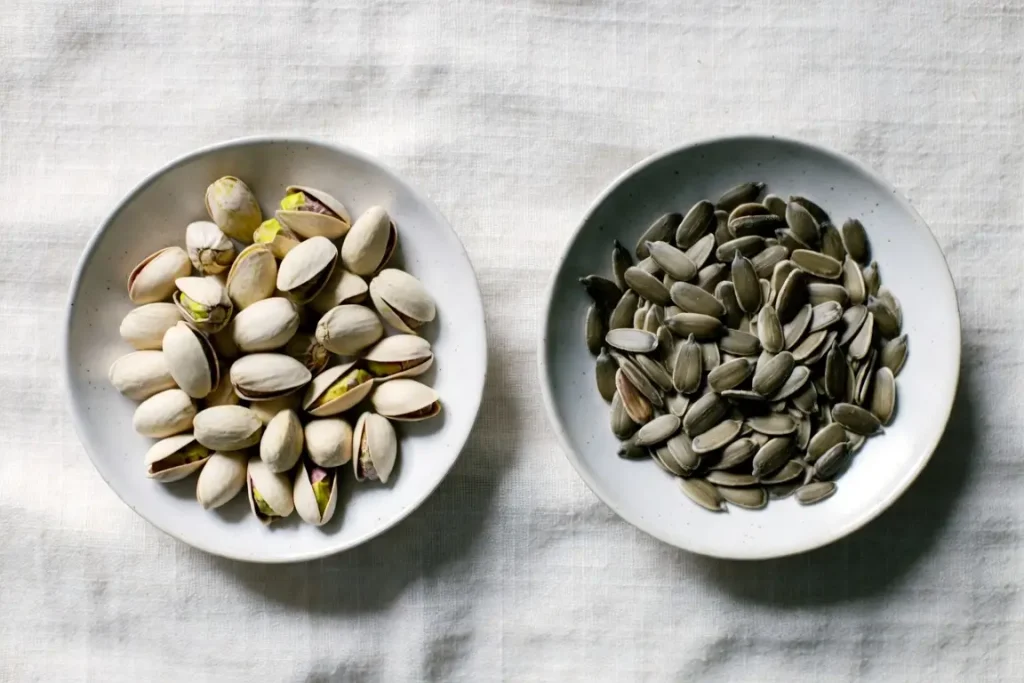 Pistachios and sunflower seeds side by side, photographed for nutritional comparison