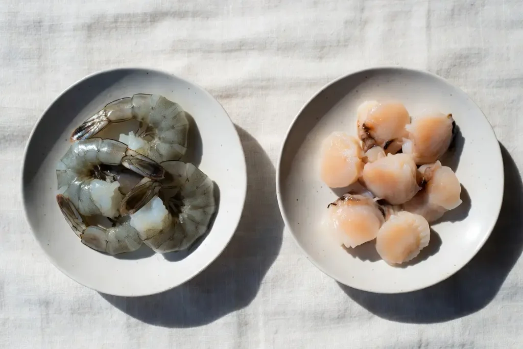 Shrimp and scallops side by side, photographed for nutritional comparison
